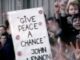 Crowd holding "Give Peace a Chance" sign.
