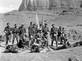 Group of soldiers posing in desert landscape.