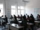 Teacher instructing students in a classroom setting.