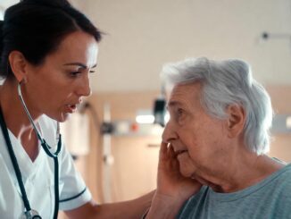 Doctor comforting elderly patient in hospital room.