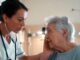 Doctor comforting elderly patient in hospital room.