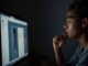 Person focused on computer screen at night.