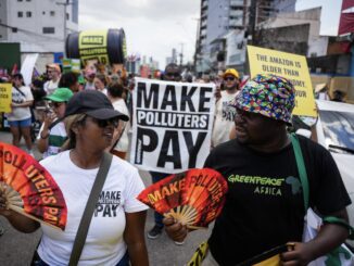 Protesters holding "Make Polluters Pay" signs.