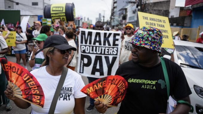 Protesters holding "Make Polluters Pay" signs.