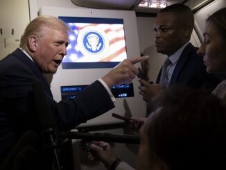Person speaking with reporters on a plane.