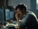 Man concentrating in front of computer screens.