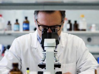 Scientist examining through a laboratory microscope.