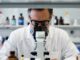 Scientist examining through a laboratory microscope.