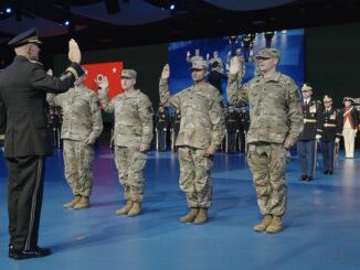 Military personnel taking an oath on stage.