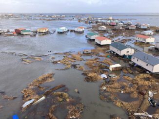 Flooded coastal village with scattered houses.