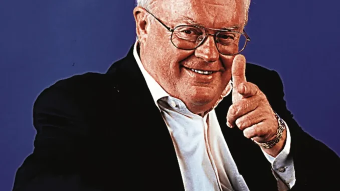 Man in suit smiling and pointing finger.