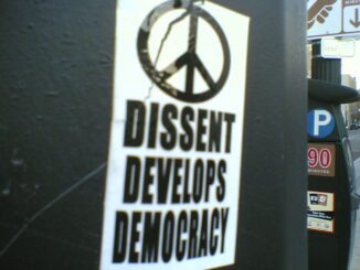 Sticker with peace sign and democracy message.