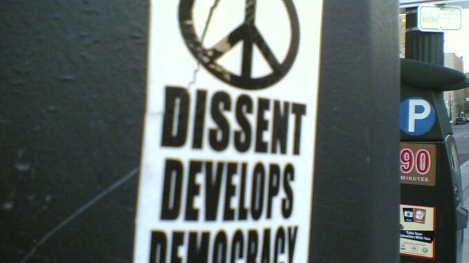 Sticker with peace sign and democracy message.