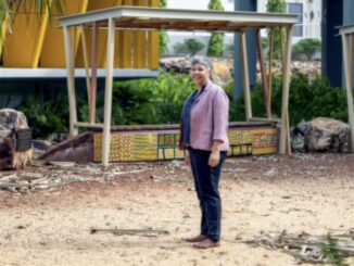 Person standing near a colorful structure outside.