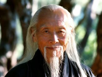 Elderly man with long white hair outdoors.