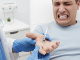 Doctor administering injection to patient's hand.