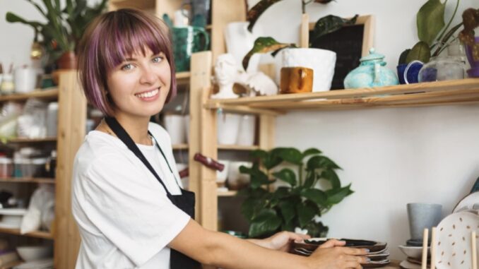 Woman organizing pottery on wooden shelves. Woman organizing pottery on wooden shelves.
