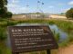 Sign near pond with government building background.