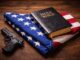 Gun, Bible, and American flag on table.