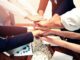 Hands joined in team unity gesture.