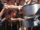 Children reaching out with pots for food.