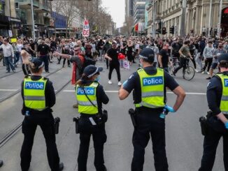 Police officers facing a crowd of protesters.