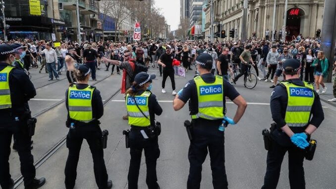 Police officers facing a crowd of protesters.
