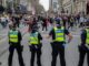 Police officers facing a crowd of protesters.