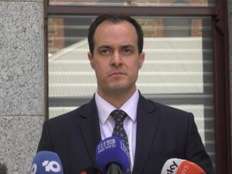 Serious speaker addressing outdoor press with microphones