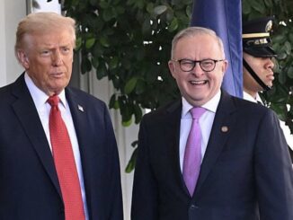 Two men standing together, smiling outdoors.