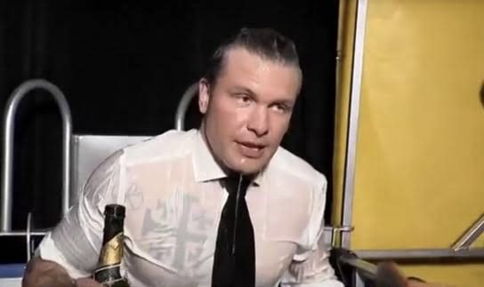 Man in wet shirt holding a bottle.