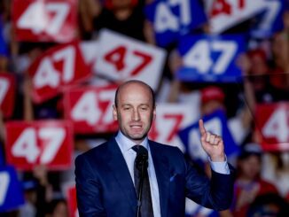 Man speaking at rally with "47" signs.