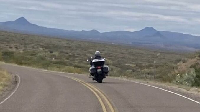 Motorcyclist riding on winding desert road.