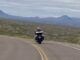 Motorcyclist riding on winding desert road.