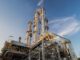 Industrial refinery towers against blue sky.