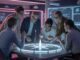 Team strategizing around illuminated digital table.