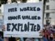 Protest sign: "Overworked, Undervalued, Exploited.