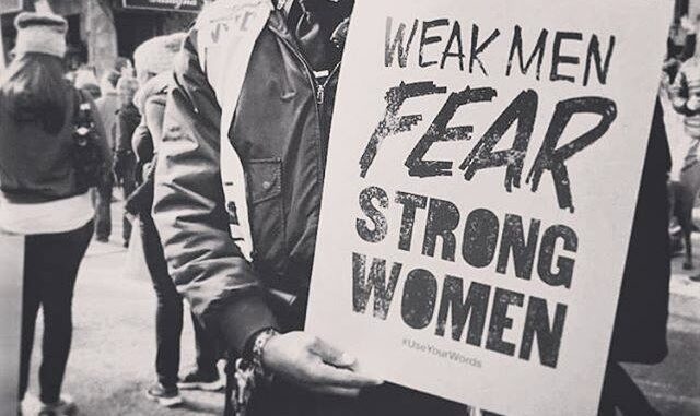 Person holding sign about strong women. Person holding sign about strong women.