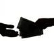 Silhouette of hands exchanging money.