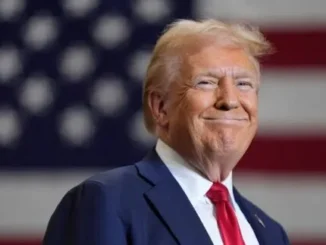 Man smiling with American flag background.