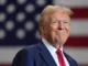 Man smiling with American flag background.