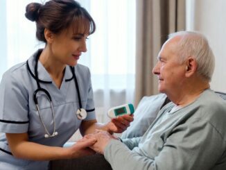 Nurse assisting elderly man with medical device.