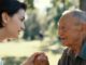 Young woman and elderly man holding hands.