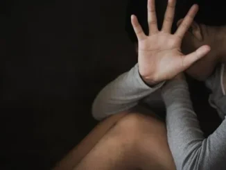 Seated person hiding face with open palm