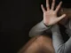 Seated person hiding face with open palm