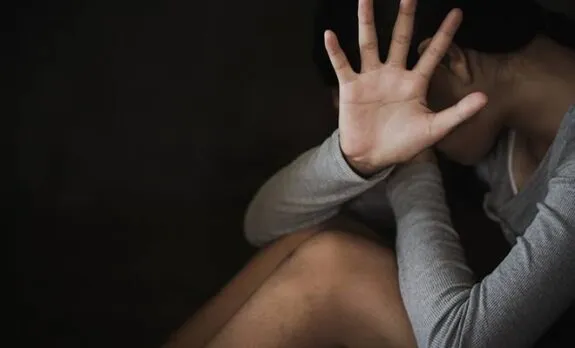 Seated person hiding face with open palm