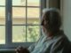Elderly man sitting by a window.