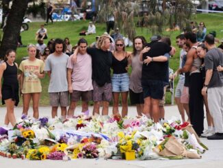 People mourning with flowers at a memorial.
