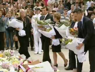 People laying flowers at a memorial ceremony.