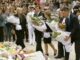 People laying flowers at a memorial ceremony.